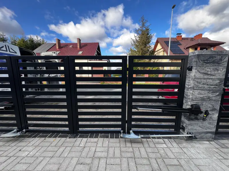 Brama dwuskrzydłowa z siłownikami i furtka na podjeździe z kostki