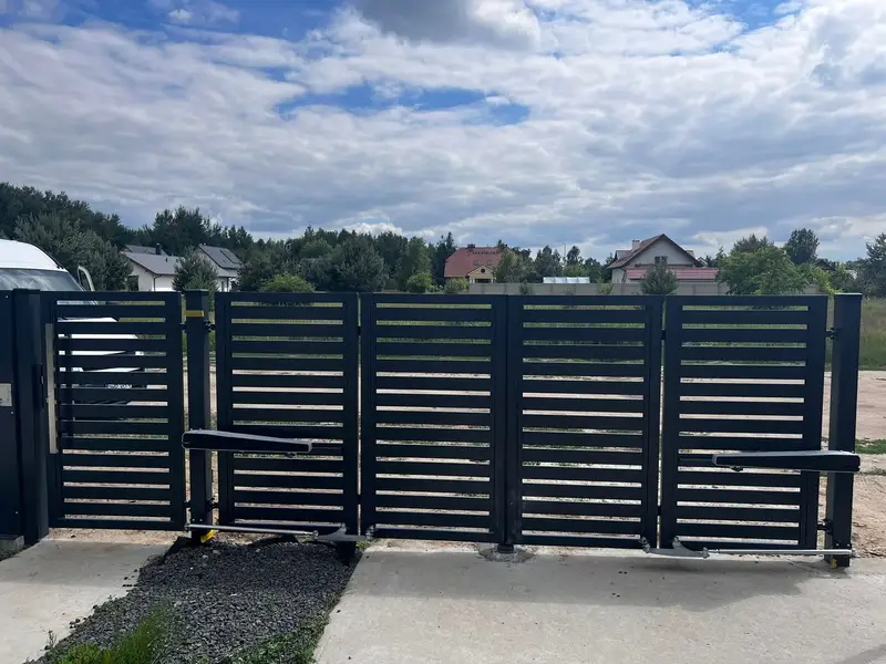 Brama harmonijkowa z napędem podczas otwierania, w tle panorama wzgórz